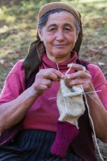Woman (62 years old) knitting socks from own sheep wool in the garden of a farmhouse in the village of Isverna, Mehedinti plateau geopark, Romania