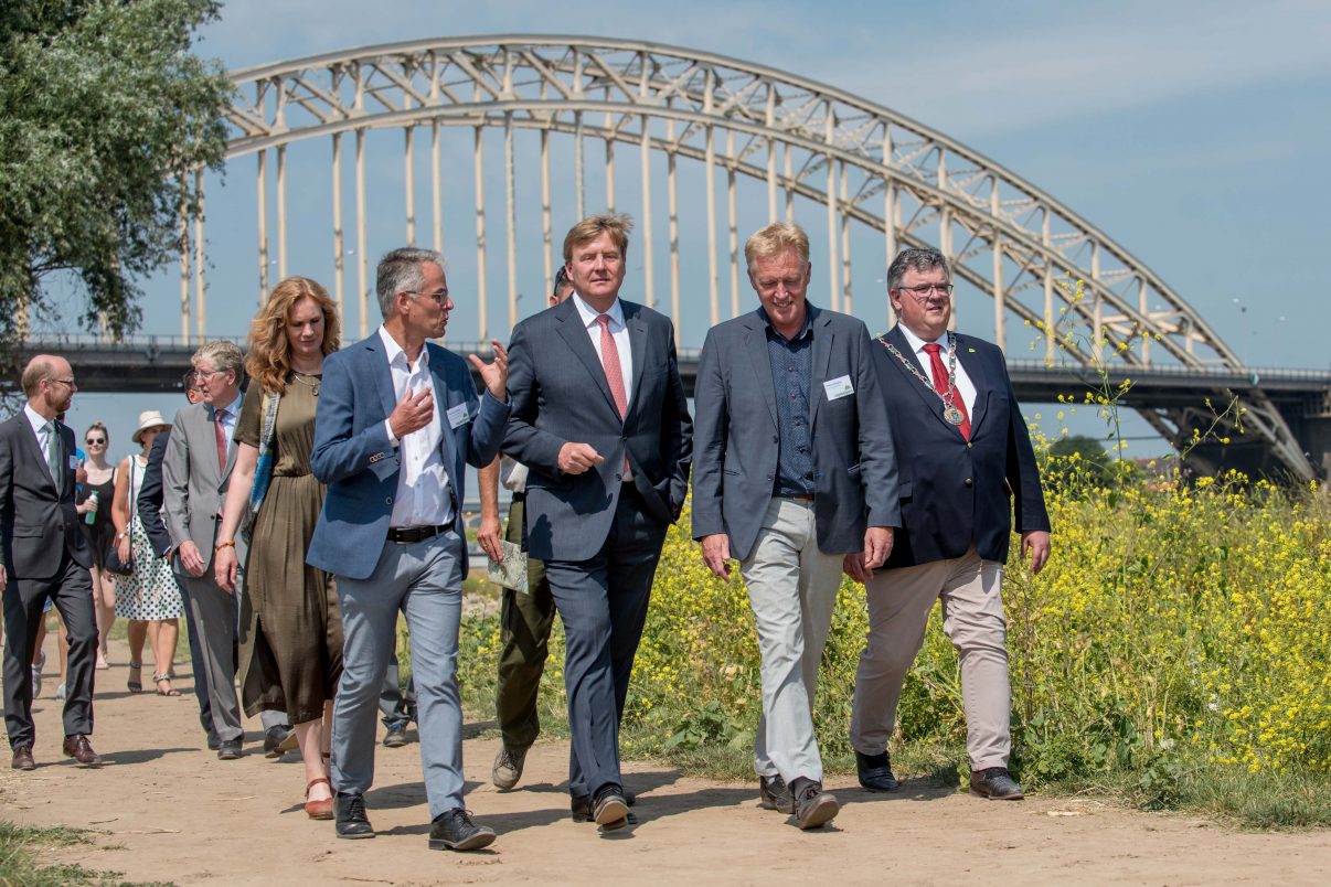 King Willem-Alexander (middle) is guided by Frans Schepers (right) and Professor Hans de Kroon (left) during a short walk on the floodplains of the River Waal. On the far left is Mrs. Harriet Tiemens (Nijmegen Municipal Council) and on the far right Mr. Hubert Bruls, Mayor of Nijmegen.