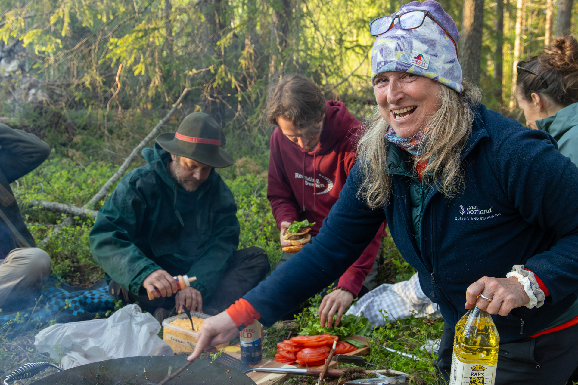 Kim Ross cooking for a group of fellow travellers on a packrafting trip on the Hjuksån river system in the Nordic Taiga, Sweden.