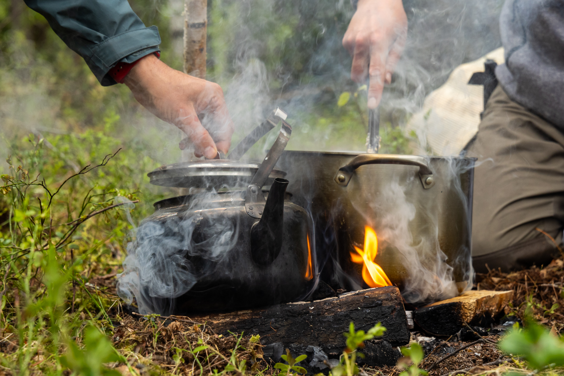 Toby Cowern making porridge over a fire for a group of fellow travellers on a packrafting trip on the Hjuksån river system in the Nordic Taiga, Sweden.