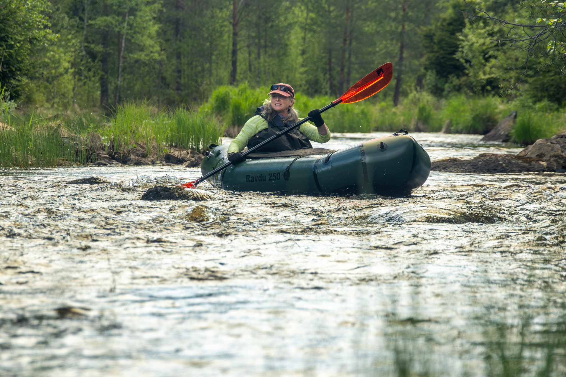 A person packrafting down the Hjuksån river system in the Nordic Taiga, Sweden.