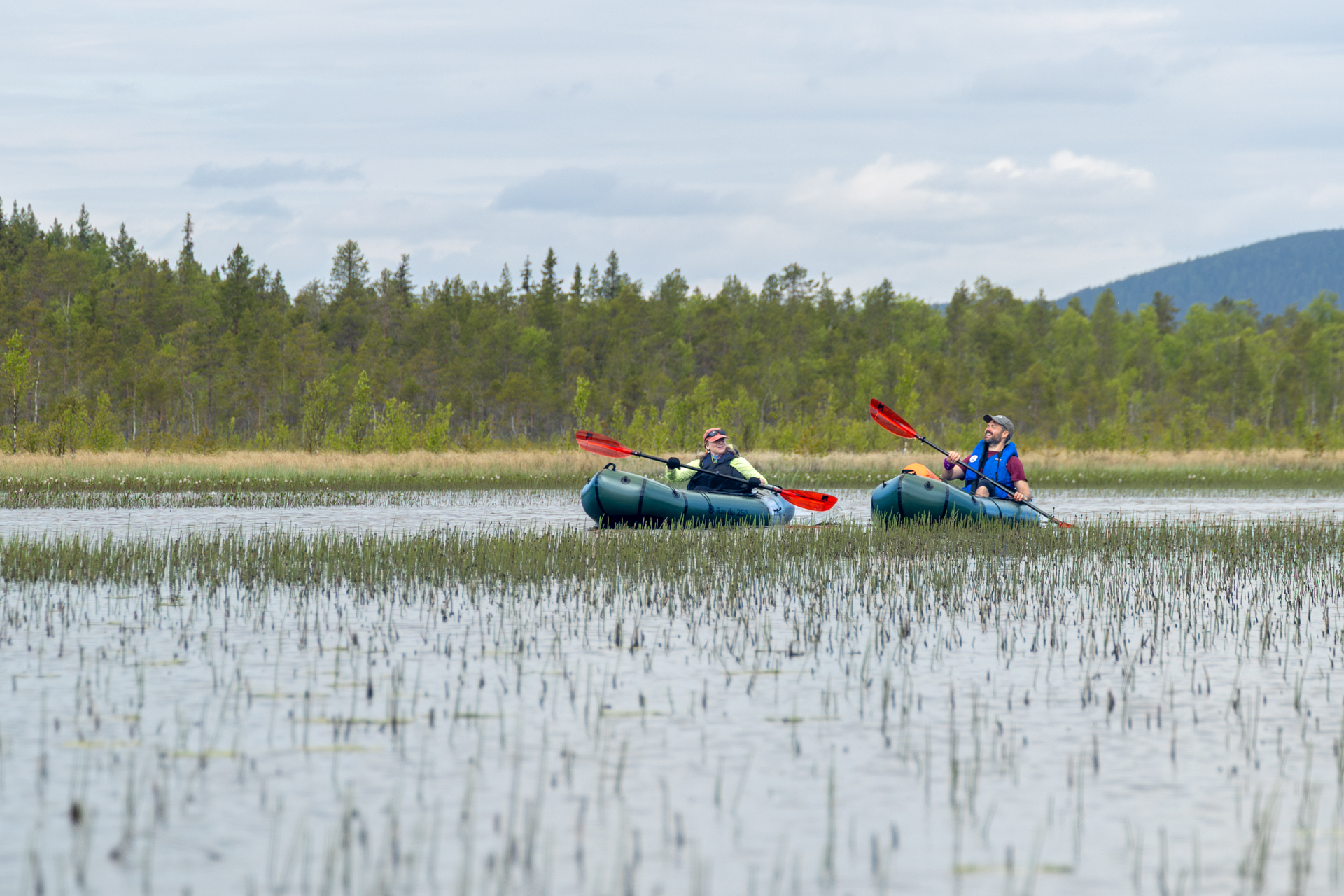 A group packrafting down the Hjuksån river system in the Nordic Taiga, Sweden.