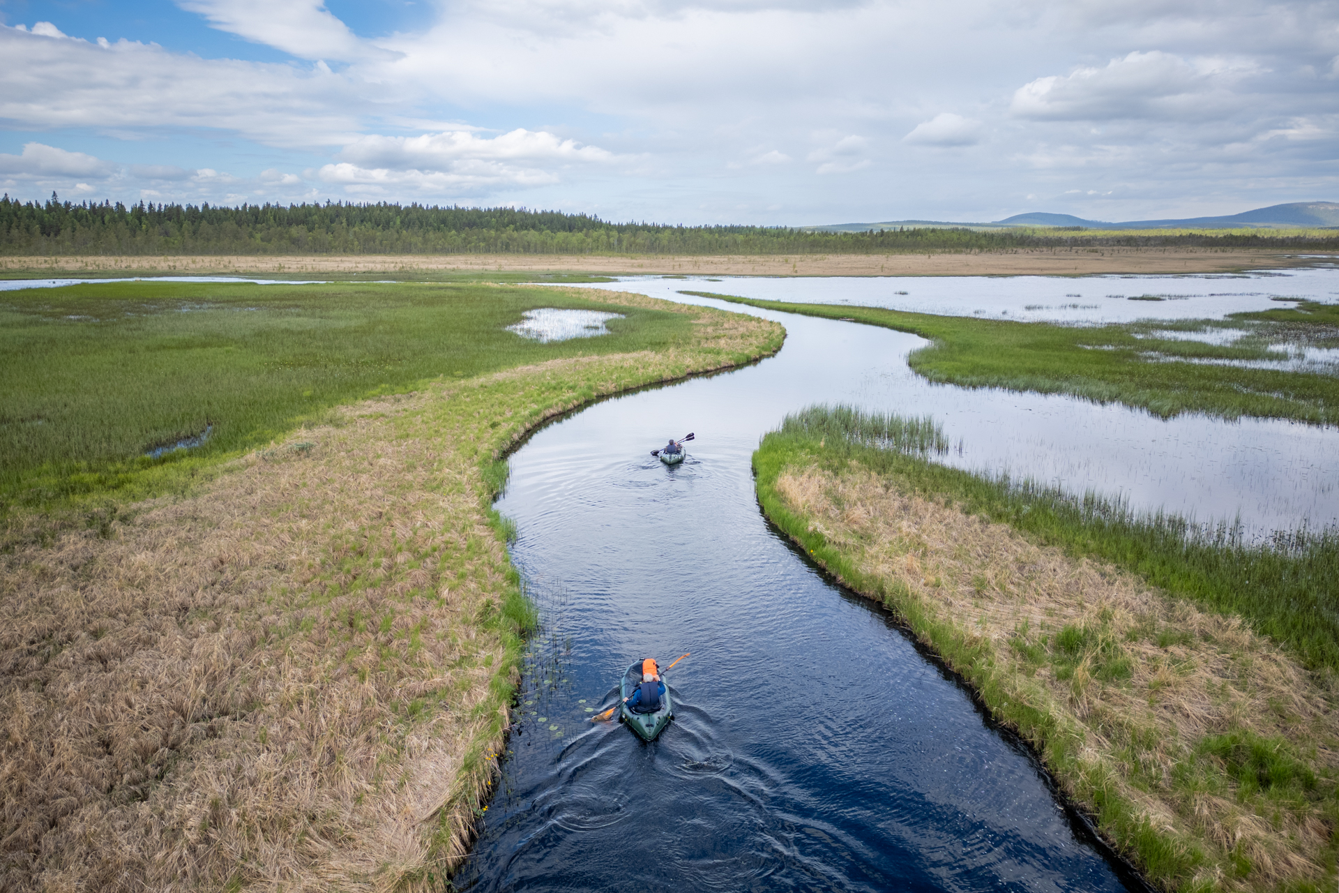 A group packrafting down the Hjuksån river system in the Nordic Taiga, Sweden.